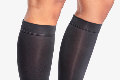 Black knee-high socks worn by a person on a light gray background